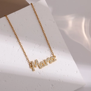 Macro shot of gold MAMA pendant necklace with sparkling rhinestones on white stone
