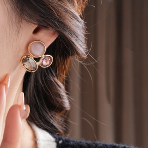 Macro detail of vintage oval earrings with cat eye stones and colorful crystals on gold base