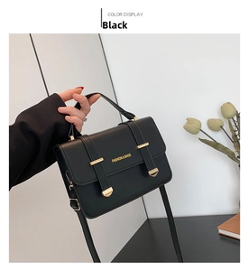 Detail of black crossbody bag with litchi texture and gold metal buckle hardware
