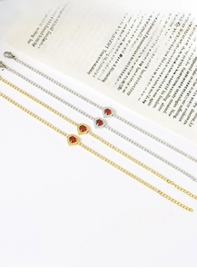 Macro shot of titanium steel heart necklaces in gold and silver with red gemstones