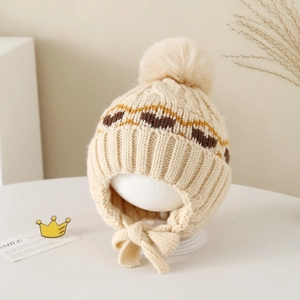 Detailed knit texture of a warm winter baby hat with pompom and earflaps