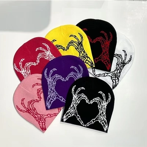Detail view of colorful knitted beanies with skeleton heart patterns in various shades