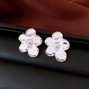 Detail of silver irregular flower earrings with white pearls and hammered metal texture