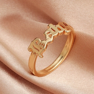 Macro shot of rose gold open ring with Baby lettering on champagne silk fabric