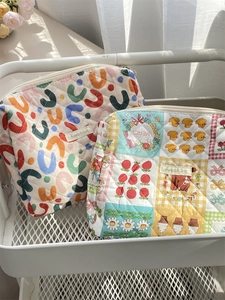 Close-up of quilted floral makeup bags with zipper and patchwork pattern on storage cart