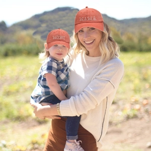 Matching orange MAMA and MINI embroidered baseball caps for mother and child outdoors