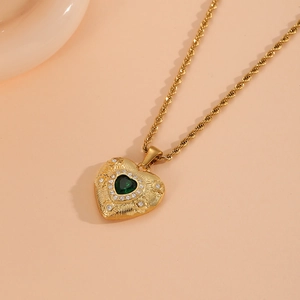 Détail macro de la chaîne torsadée dorée avec pendentif cœur et pierre verte