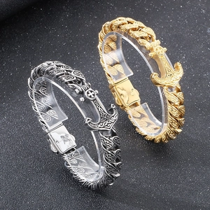Detail of punk retro cross anchor and vine patterned Cuban link bracelets in silver and gold