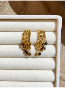 Detailed close-up of retro irregular tassel earrings with golden resin and tiger eye beads
