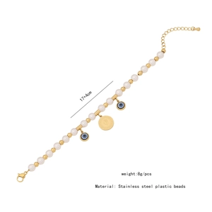 Detail showing gold stainless steel bracelet with white pearls and blue evil eye charm
