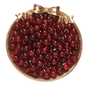 Macro view of red crackle beads for jewelry making in a decorative golden tray