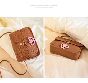 Detailed view of brown leather bag with embossed cartoons and pink heart charm