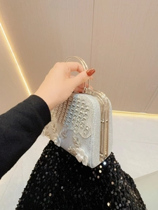 Detailansicht einer silbernen Abendtasche mit 3D-Blumenapplikationen und glitzernden Strasssteinen