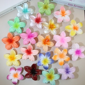 Close-up of vibrant frangipani flower hair claws in multiple gradient colors and glossy finish