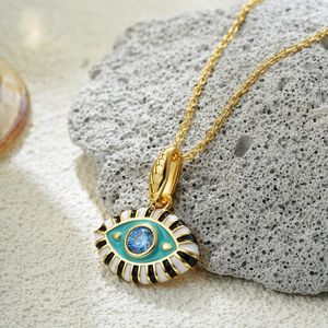 Macro shot of gold 18K Evil Eye pendant with colorful enamel on natural stone