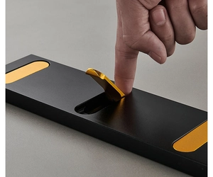 Close-up showing a hand pressing the folding mechanism of a black and gold wall hook