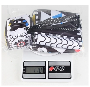 Detail showing high-contrast newborn cloth book on a digital scale weighing 110g