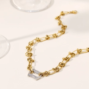 Elegant gold rope chain necklace with a horseshoe diamond pendant on beige background