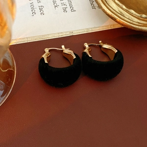 Dettaglio di orecchini a cerchio a U dorati e velluto nero dallo stile retrò elegante