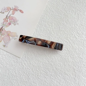 Macro detail of rectangle acetate hair clip with brown and blue marble texture