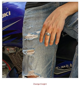 Detail of vintage punk skull wing ring worn by a biker on a motorcycle seat