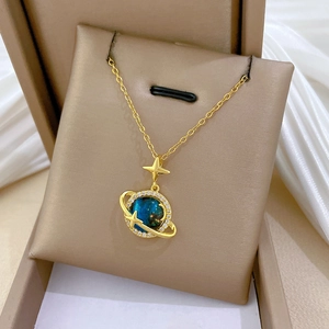 Dettaglio della collana celeste dorata con pendente pianeta blu in una scatola regalo