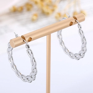 Détail de boucles d'oreilles créoles torsadées argentées sur un présentoir à bijoux