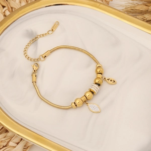 Bracelet doré en acier inoxydable avec breloques œil et feuille en strass sur plateau