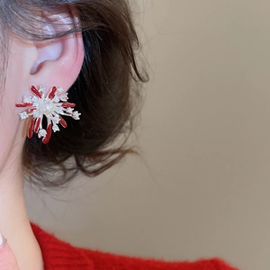 Close-up of elegant fireworks stud earring with red enamel and central pearl on model