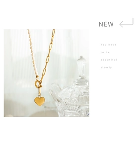 Detail of heart pendant necklace featuring freshwater pearls and gold paperclip chain