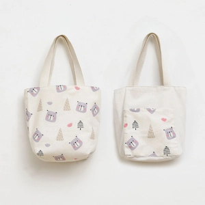 Detail of two beige canvas tote bags with cartoon bear and hand-drawn tree prints
