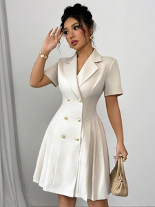 Detailoverzicht van beige double-breasted jurk met taille-accent en plooirok