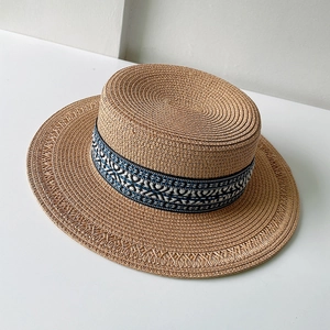 Dettaglio del cappello di paglia piatto boho con nastro intrecciato a motivi etnici