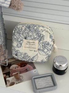 Vue détaillée de la pochette en coton matelassé à fleurs avec produits de beauté