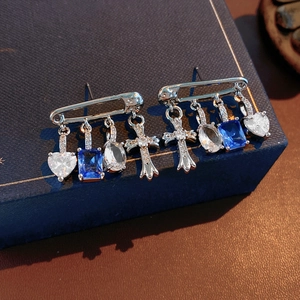 Detailed shot of silver pin earrings with blue heart and cross zirconia on dark box