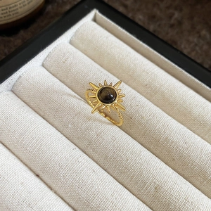 Detail of tiger eye sunburst ring with twisted band inside a beige velvet jewelry box