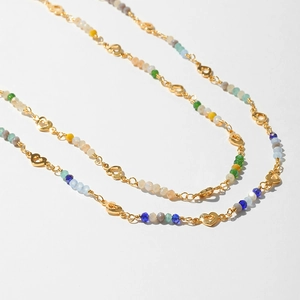 Detail of colorful faceted beads and hollow heart link on a golden bohemian necklace