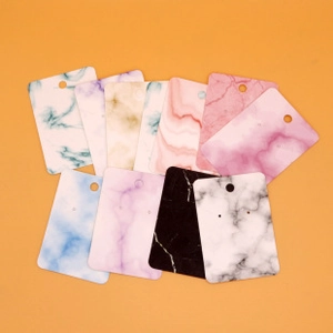 Flat lay of colorful marble pattern jewelry display cards on a bright orange background