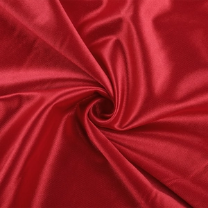 Vue détaillée du tissu satiné rouge luxueux montrant une texture lisse et des plis élégants