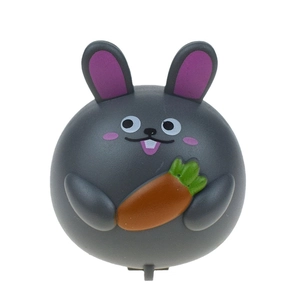 Close-up of a cute grey round bunny toy holding an orange carrot for Easter fun