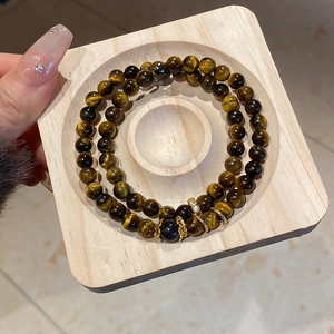 Detail view of double-layered tiger eye bead bracelet with golden hollow floral accents