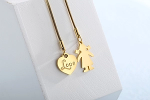 Detail view of gold heart pendant with Love engraving and girl charm on snake chain