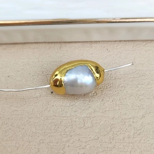 Macro shot of a baroque freshwater pearl with golden plated metal trim for jewelry DIY