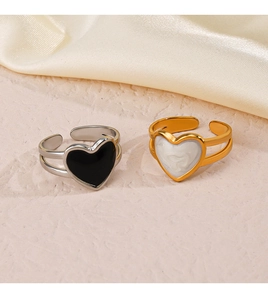 Detailed view of two heart-shaped open rings in silver-black and gold-white on beige base