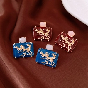 Macro view of vintage enamel plum blossom earrings in burgundy and navy blue tones