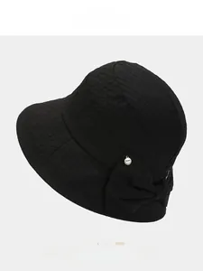 Detail of black bow bucket hat with textured fabric and small round metal emblem