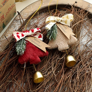 Plush Christmas bell ornaments with red and beige ribbons on a rustic wooden tray
