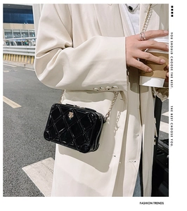Detail of black quilted PVC jelly bag with gold chain strap on a trench coat model