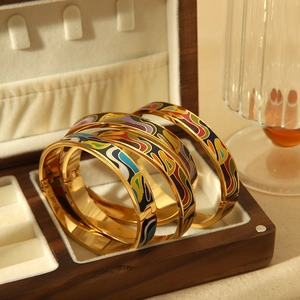 Close-up of enamel colorful wave pattern gold bangles on a luxury wooden jewelry box