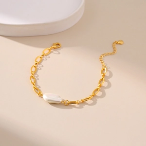 Macro detail of gold link bracelet with an irregular baroque pearl and lobster clasp